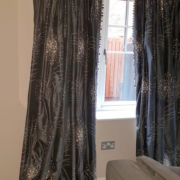 A pair of curtains hung up to measure for their drop alteration